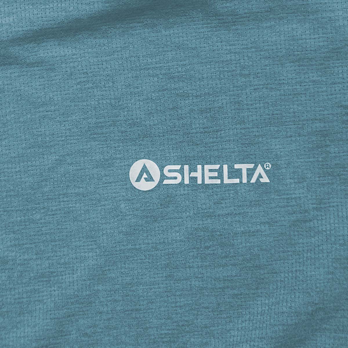Close-up of a blue fabric surface with a Shelta logo.