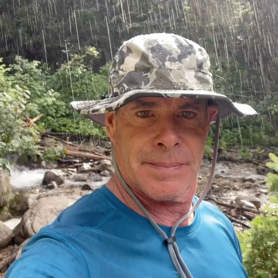 a man wearing a shelta sun hat while walking in the rain