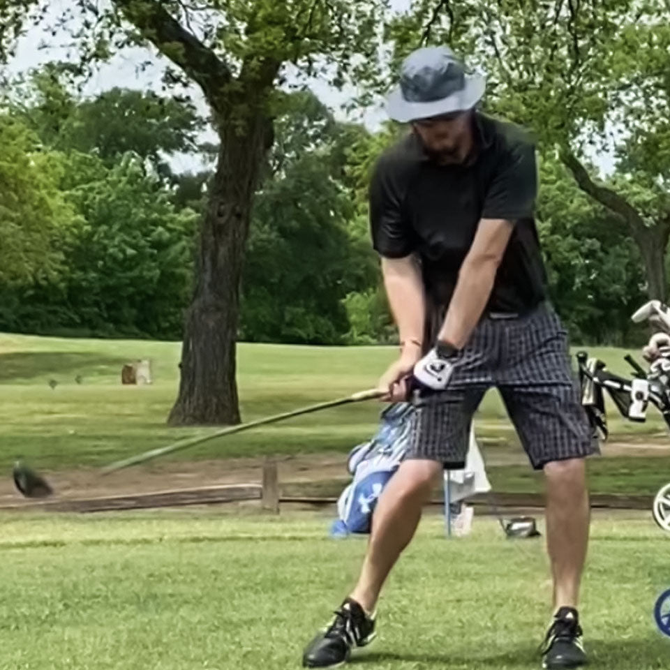 a man swinging a golf club while wearing a shelta sun hat