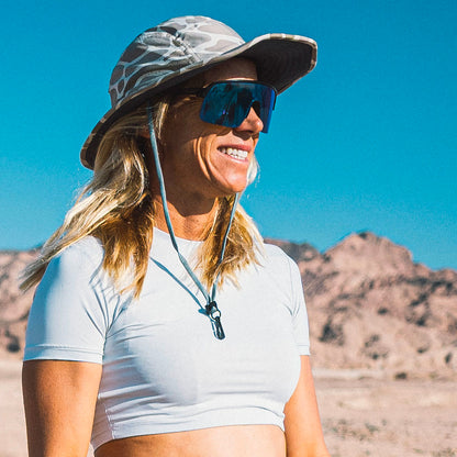 Woman wearing a wide-brimmed hat and sunglasses in a desert setting