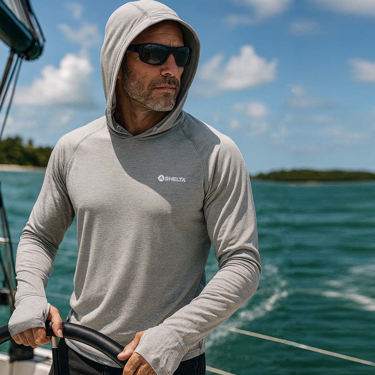 Man wearing a gray hoodie with a brand logo on a boat with water and sky in the background