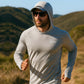Man wearing a gray hoodie with a brand logo, running outdoors with mountains in the background.