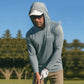 Man in a gray hoodie and sunglasses holding a golf club on a golf course