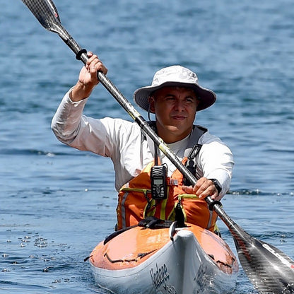 Man paddling a kayak on calm water wearing a life jacket and hat.