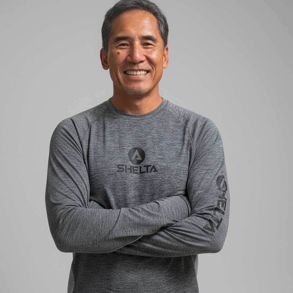 Man wearing a gray long-sleeve shirt with a brand logo on a gray background