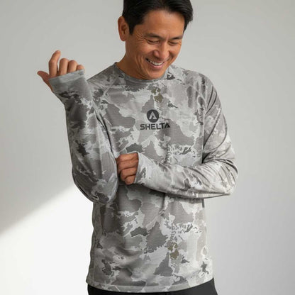 Man wearing a gray camouflage shirt with 'SHELTA' logo on a light gray background
