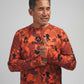Man wearing an orange camouflage shirt with a brand logo on a gray background