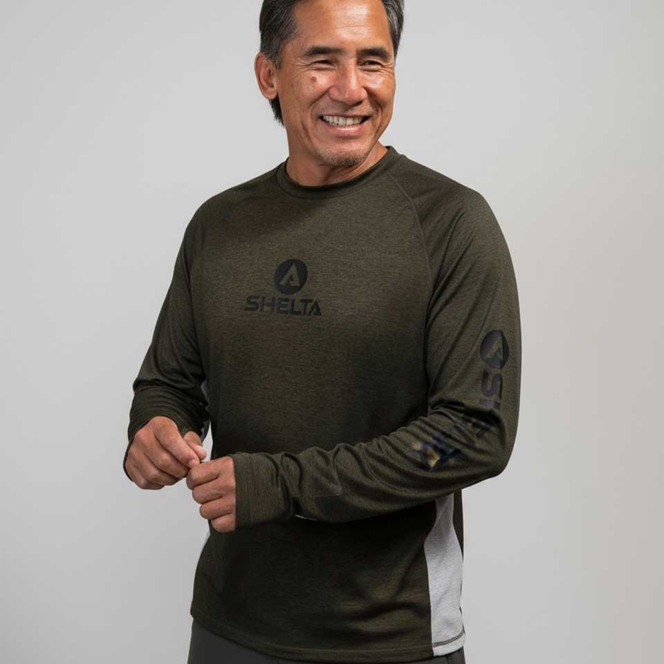 Man wearing a green long-sleeve shirt with a Shelta logo on a plain background
