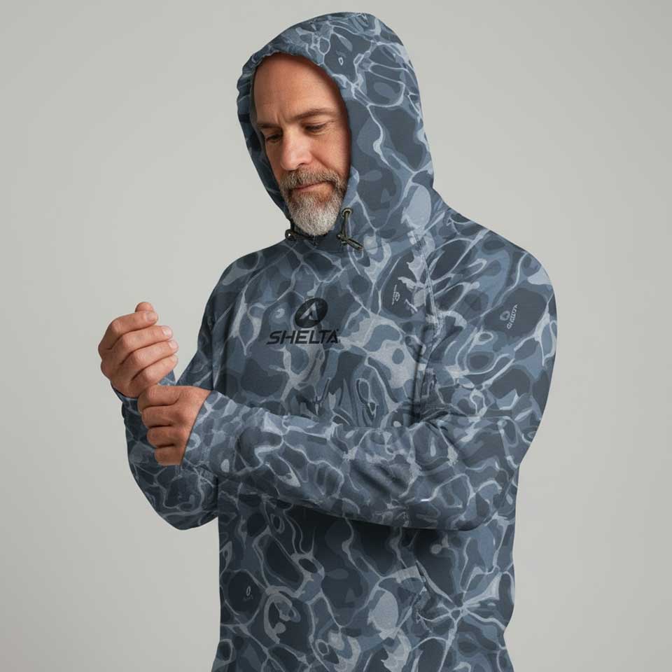 Man wearing a blue camouflage hooded jacket with a brand logo on a gray background