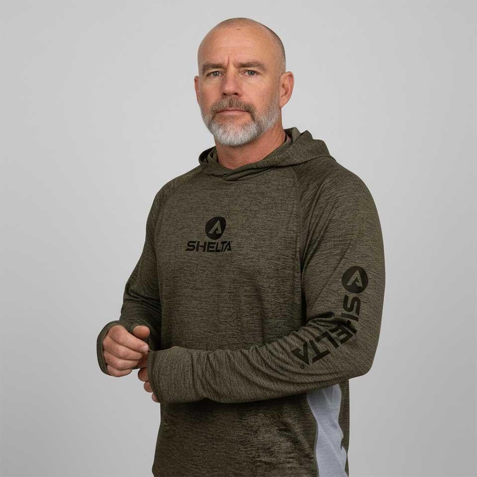 Man wearing a green hoodie with 'SHELTA' logo on a gray background