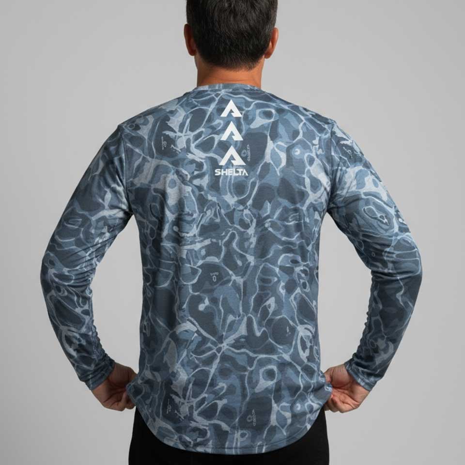 Person wearing a blue camouflage long-sleeve shirt with a brand logo on the back against a gray background