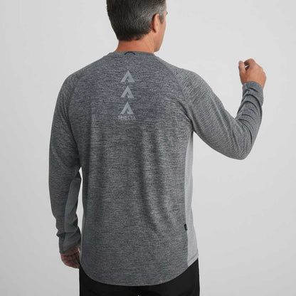 Man wearing a gray long-sleeve shirt with a logo on the back against a light gray background