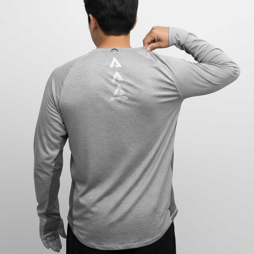 Person wearing a gray long-sleeve shirt with a logo on the back against a light gray background