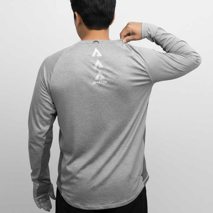 Person wearing a gray long-sleeve shirt with a logo on the back against a light gray background