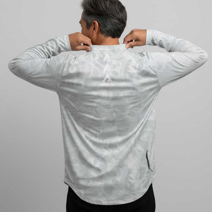 Person wearing a white long-sleeve shirt with a subtle pattern on a gray background