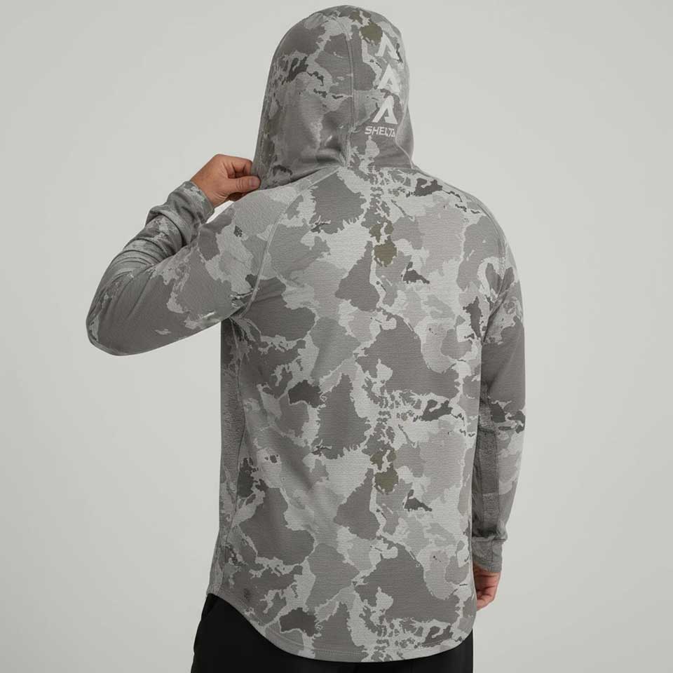 Person wearing a gray camouflage hoodie with a brand logo on the back against a light gray background