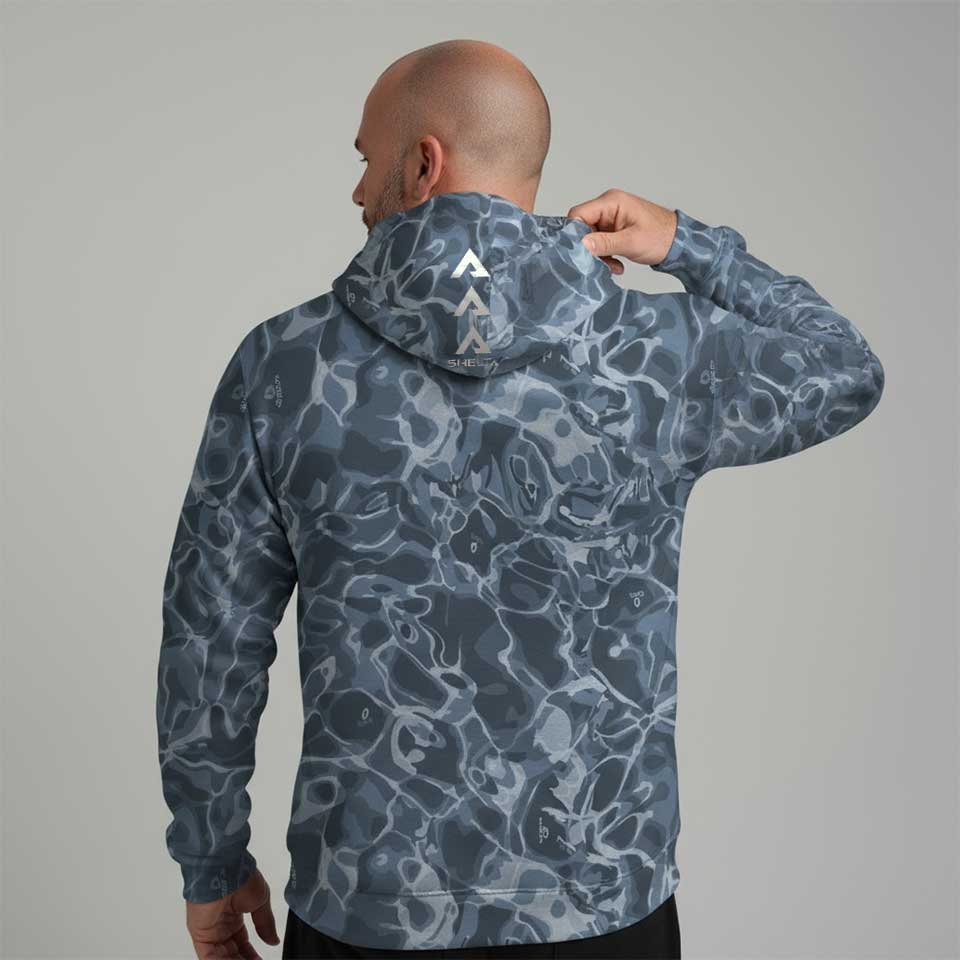 Person wearing a blue camouflage hoodie with a brand logo on the back against a gray background