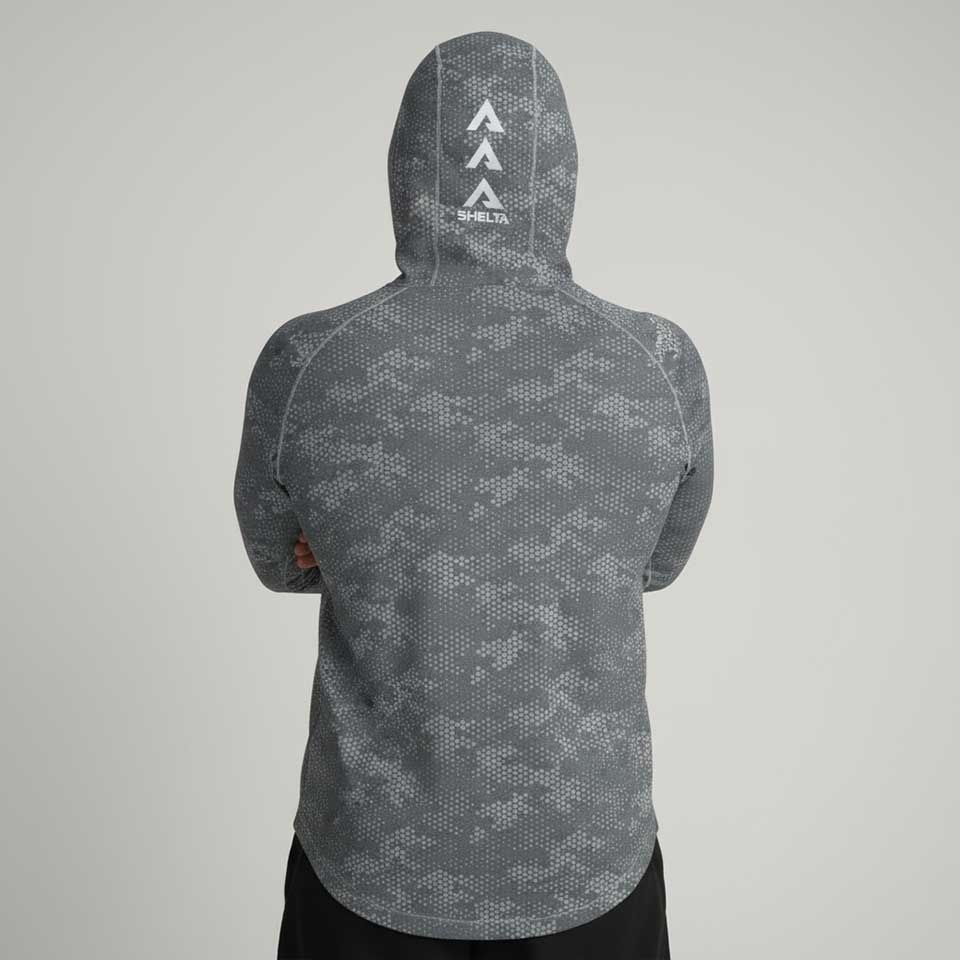 Person wearing a gray patterned hoodie with a brand logo on the back against a light gray background
