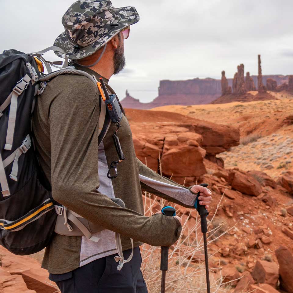 Hiker with backpack and walking sticks in a desert landscape