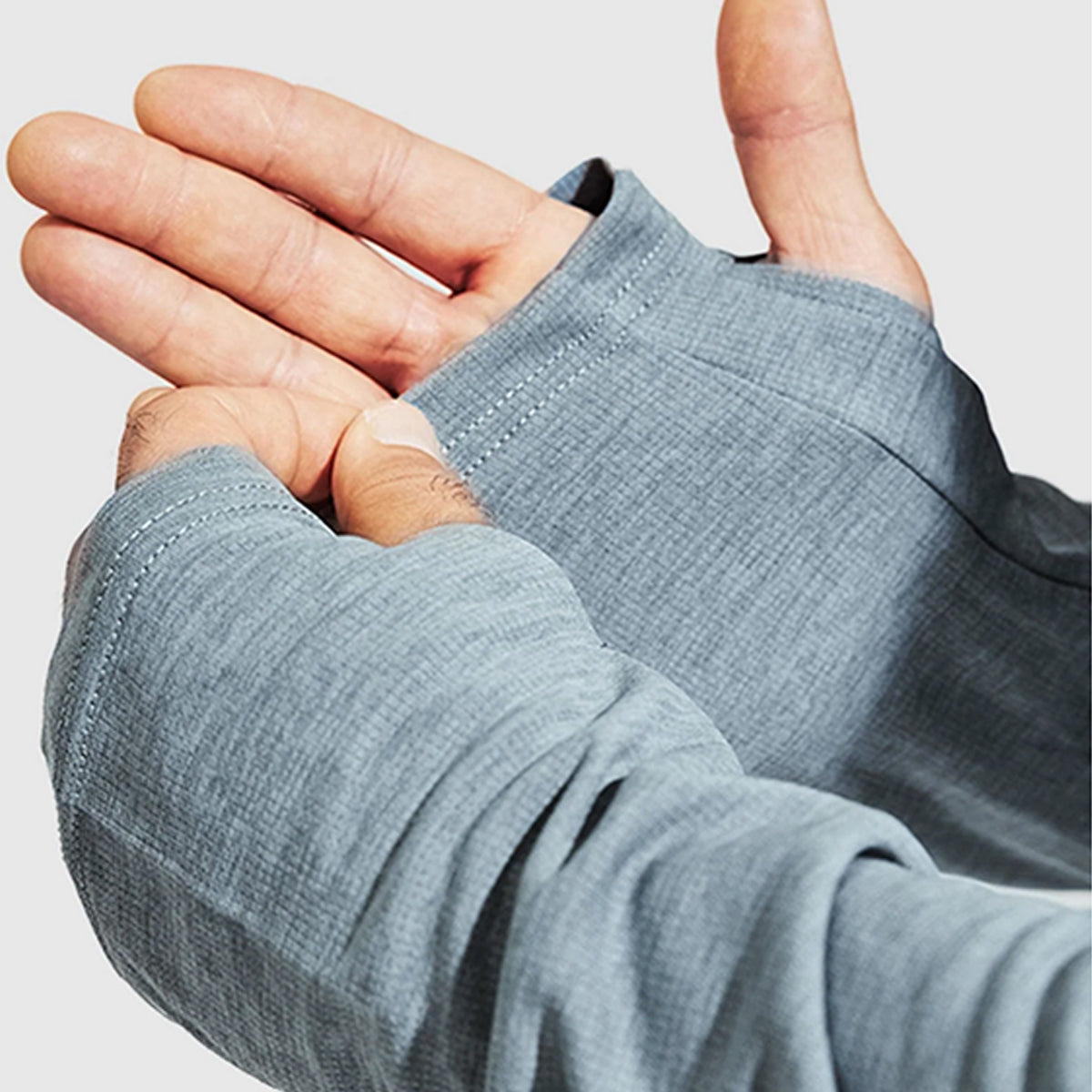 Close-up of a person wearing a textured gray sleeve on a light gray background