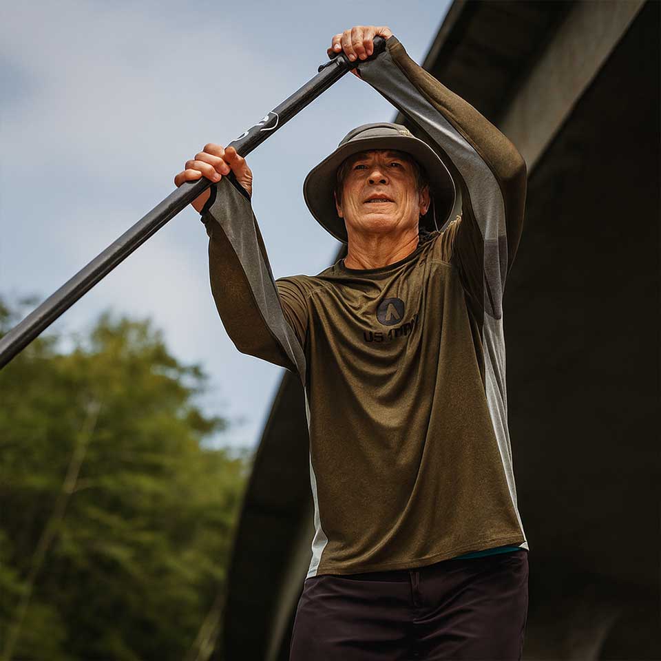 Man holding a long tool against a natural background