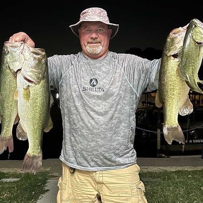 Man holding four large bass in a dark outdoor setting