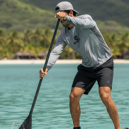 Person paddleboarding in a tropical setting with palm trees and a beach in the background.