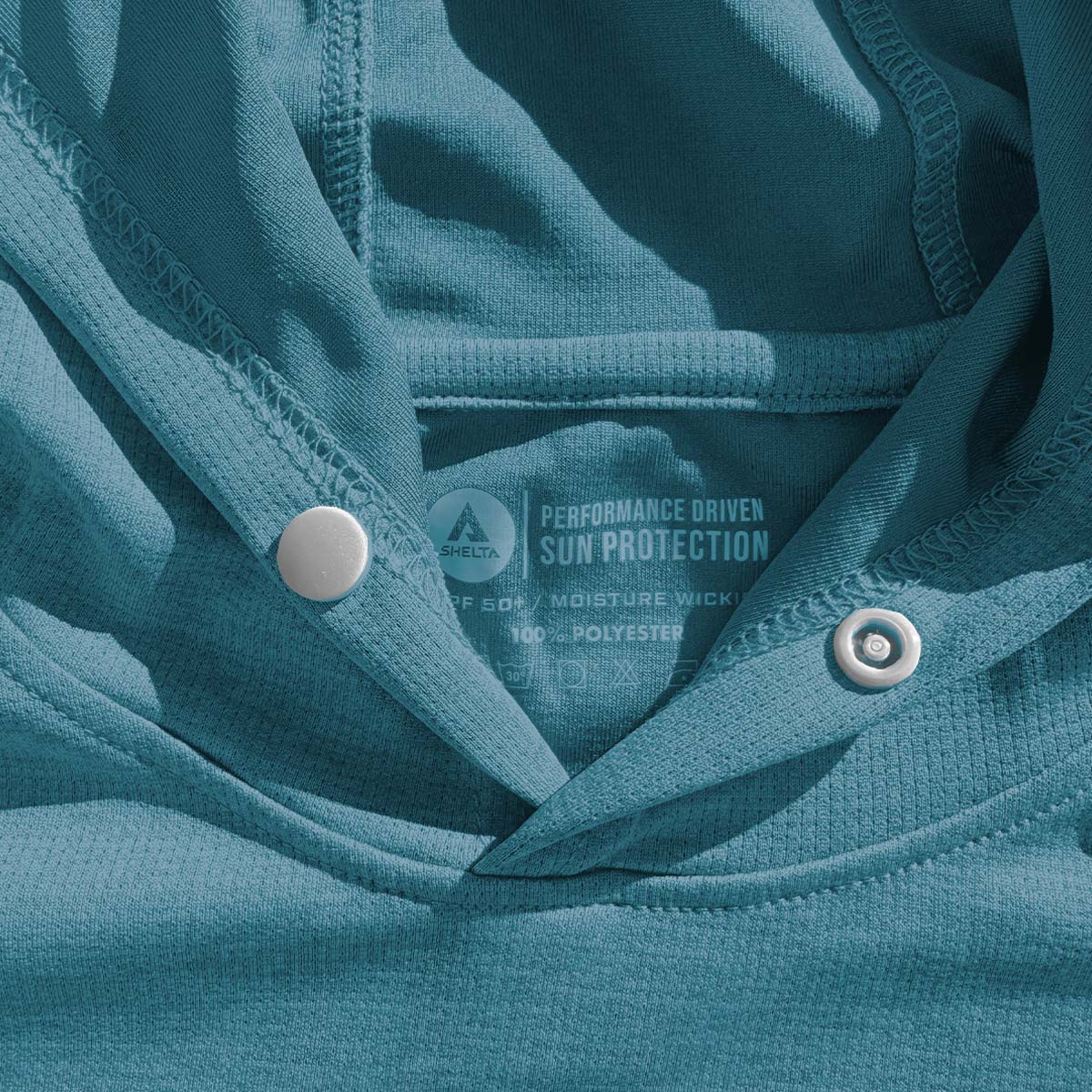 Close-up of a teal fabric with buttons and a performance label.
