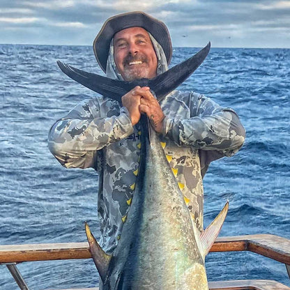 Man holding a large fish on a boat with ocean in the background