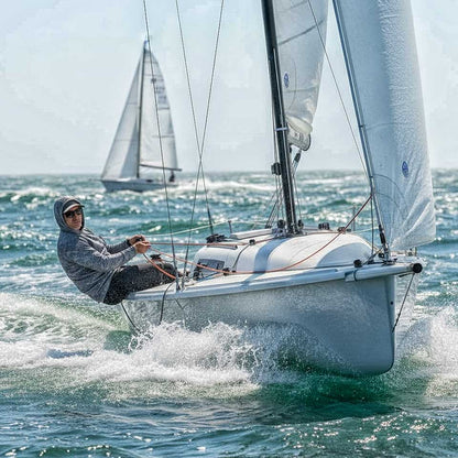 Person sailing a white sailboat on choppy waters with another sailboat in the background.