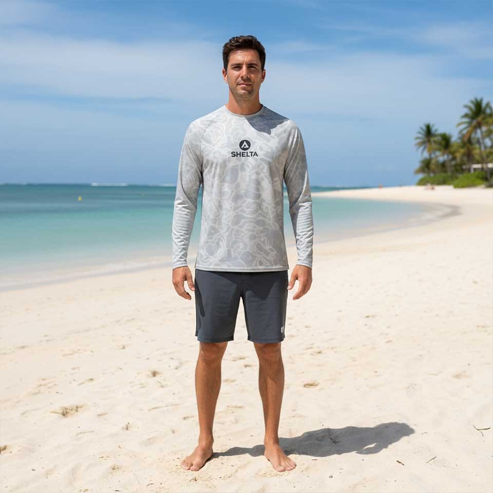 Man wearing a gray long-sleeve shirt with a brand logo on a beach