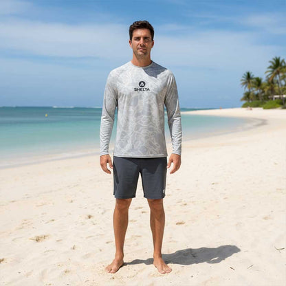 Man wearing a gray long-sleeve shirt with a brand logo on a beach