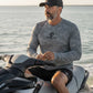 Man sitting on a jet ski wearing a Shelta branded shirt with water in the background