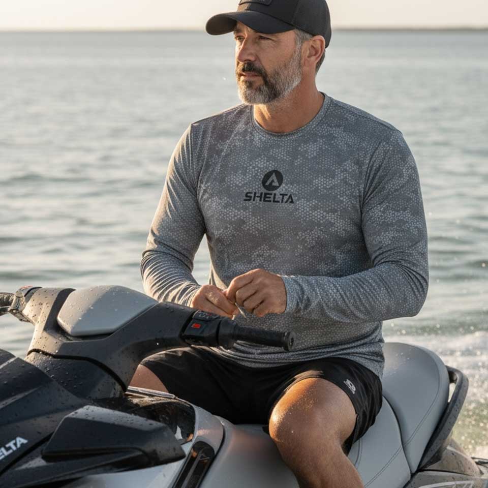 Man sitting on a jet ski wearing a Shelta branded shirt with water in the background