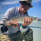 Man holding a fish caught while fishing on a boat