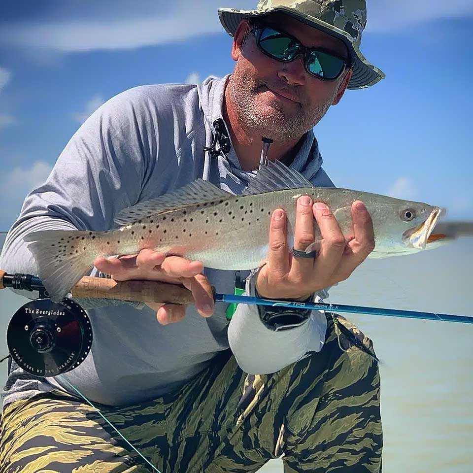 Man holding a fish caught while fishing on a boat