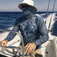 Person on a boat wearing a blue camouflage shirt with a brand logo, sitting at the helm.