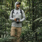 Man in a forest wearing a Shelta hoodie and holding a camera