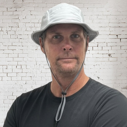 Man wearing a white bucket hat against a white brick wall