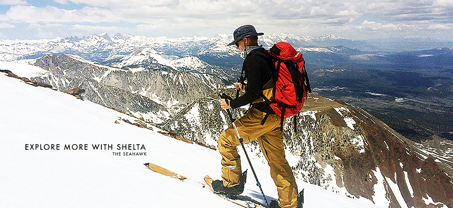 Picture of man on cross county skis with mountains in the background wearing a shelta sun hat