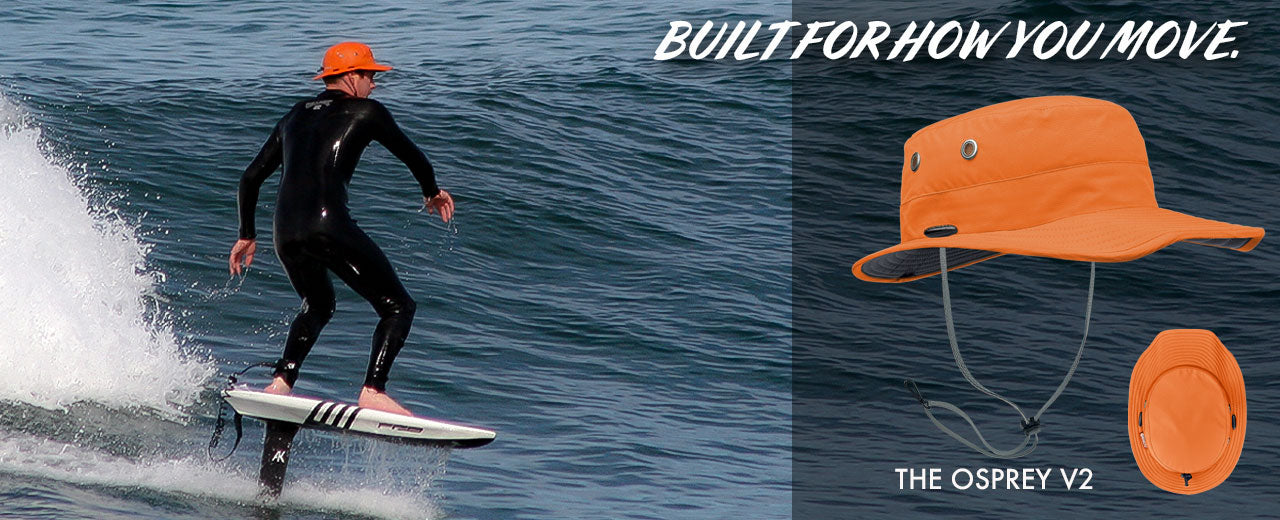 Person surfing with an orange Osprey V2 hat on a blue ocean background