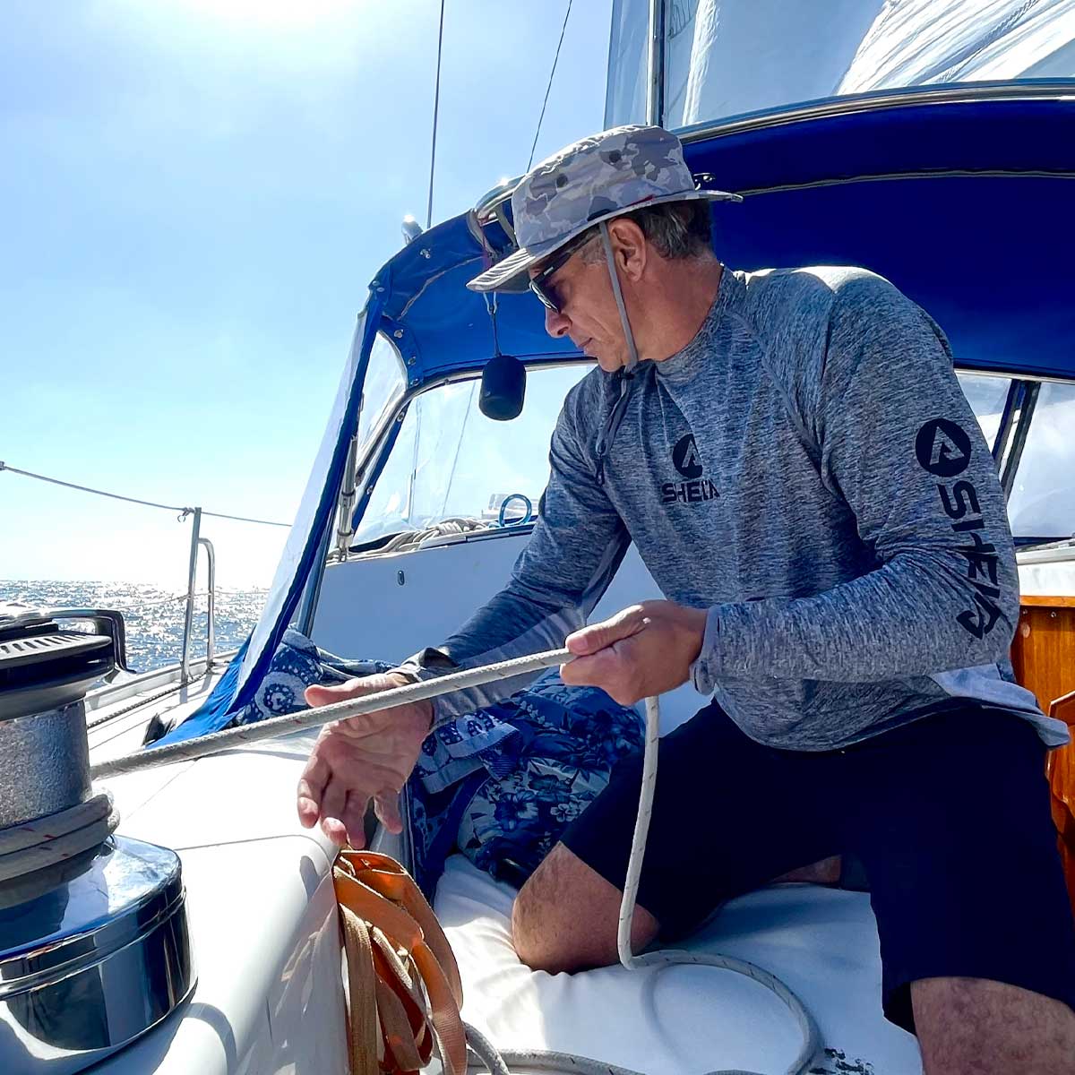 A man sailing wearing a shelta sun hat and aquaterra sun shirt