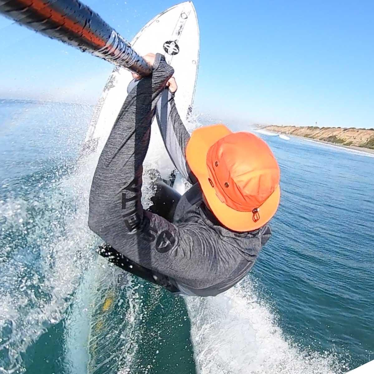 a man hitting the lip on a paddle board wearing a shelta sun hat and aquaterra sun shirt