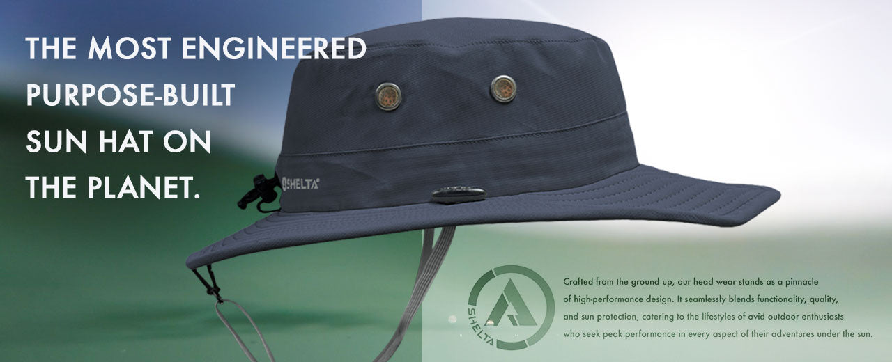 A dark navy blue wide-brim sun hat with a chin strap, displayed on a split green and light gray background with promotional text and a small logo. The hat has two small round metal eyelets 