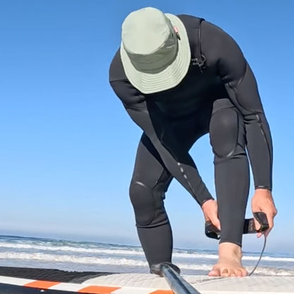 MAN PUTTING ON HIS SURF LEAsh while wearing a shelta osprey