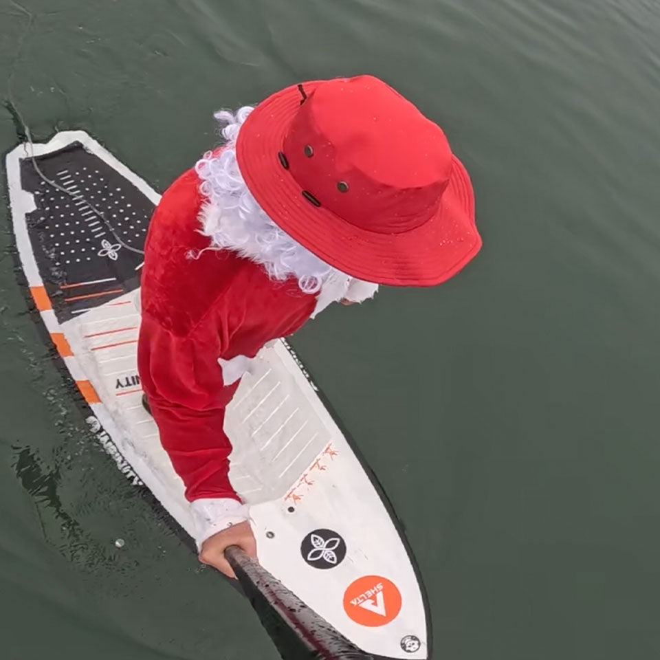 a view from above of santa wearing a red shelta sun hat while paddle boarding