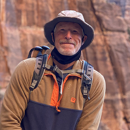 Man with a Seahawk hat on hiking