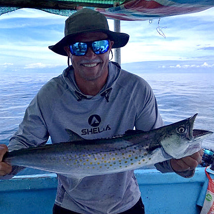 Fisherman holding big fish wearing Shelta Hat with Shelta Sun Shirt