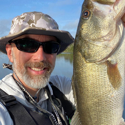 Fisherman holding fish wearing a Raptor sun hat