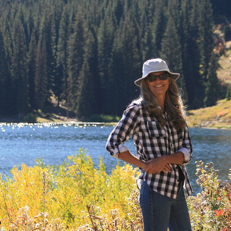 Image of women wearing Light Silver Land Hawk Sun Hat with a lake behind her
